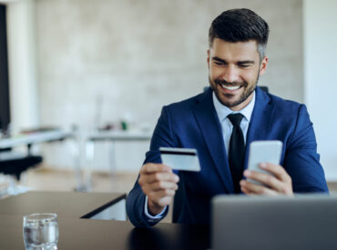 Happy entrepreneur online banking with credit card and mobile ph